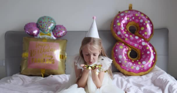 Indoor shot van mooie vrolijke schattige schattige meisje kind vieren acht jaar oude verjaardag met heldere en kleurrijke ballonnen, het dragen van casual modieuze jurk. Dat joch heeft plezier. Langzame beweging — Stockvideo