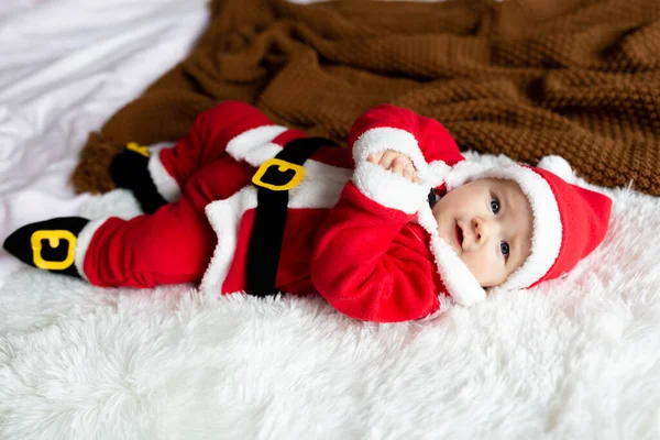 Κοντινό πορτραίτο νεογέννητου μωρού. Χαριτωμένο Καυκάσιο κοριτσάκι 4-5 μηνών με στολή Αϊ Βασίλη ξαπλωμένο σε πλεκτή κουβέρτα στο κρεβάτι. Καλά Χριστούγεννα Χριστούγεννα και ευτυχισμένο το 2022 — Φωτογραφία Αρχείου