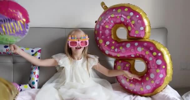 Plan intérieur de jolie fille adorable mignon joyeux enfant célébrant huit ans anniversaire avec des ballons lumineux et colorés, portant une robe décontractée à la mode. Un gamin qui s'amuse. Mouvement lent — Video
