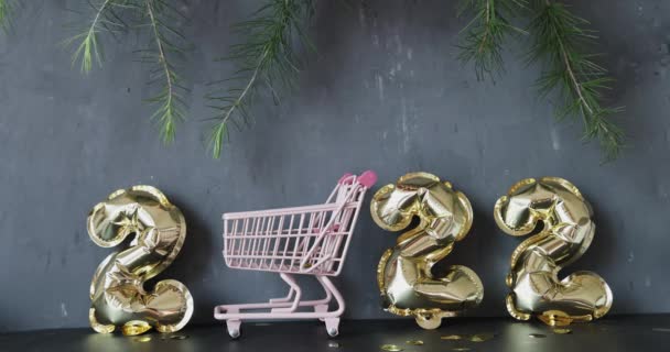 Feliz ano novo 2022 fundo. Balões metálicos cor dourada em concreto cinza com confete. Celebração de férias de inverno. Movimento lento — Vídeo de Stock