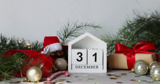 С новым 2022 годом! Календарь с датой 31 декабря на сером бетоне с упакованной подарочной коробкой и конфетти. Зимние праздники. Медленное движение — стоковое видео