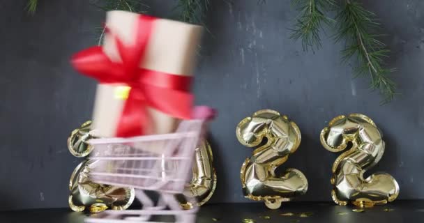 С новым 2022 годом! Металлические шарики золотого цвета на сером бетоне с конфетти. Зимние праздники. — стоковое видео