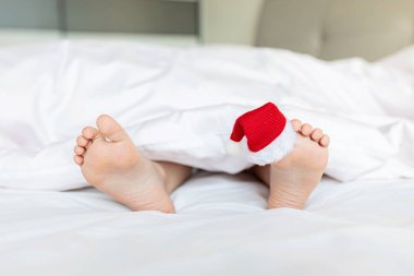 Başparmağında kırmızı Noel Baba şapkası olan çocuk ayakları. Fotokopi alanı ile çıplak ayaklı Noel konsepti. Mutlu yıllar 2022 ve Xmas tatil rahatlama konsepti.