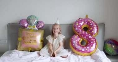 Hoş, sevimli, sevimli bir kızın, sekiz yaşındaki doğum gününü parlak ve renkli balonlarla kutladığı, günlük moda elbiseler giydiği bir fotoğraf. Çocuk eğleniyor. Yavaş çekim