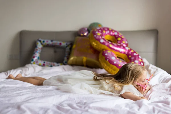 Indoor shot van mooie vrolijke schattige schattige meisje kind vieren acht jaar oude verjaardag met heldere en kleurrijke ballonnen met inscriptie woorden blijven fantastisch, het dragen van casual modieuze jurk — Stockfoto