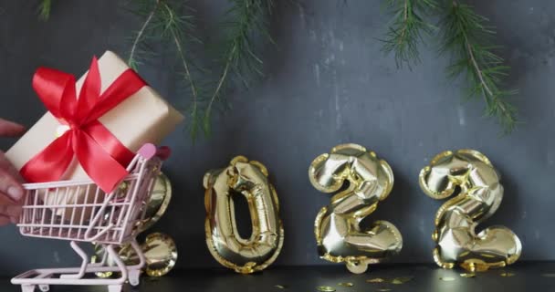 Frohes neues Jahr 2022 Hintergrund. Metallische Luftballons goldene Farbe auf grauem Beton mit Konfetti. Winterfest. Zeitlupe — Stockvideo