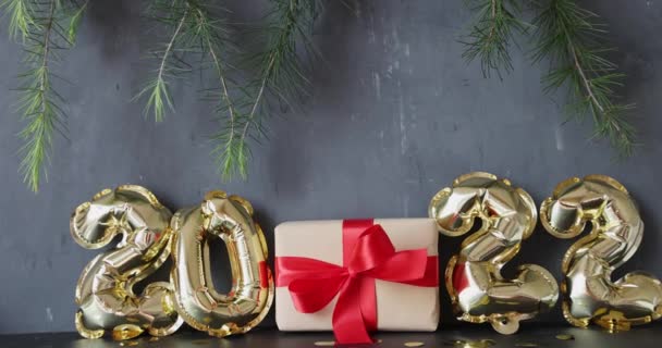 Frohes neues Jahr 2022 Hintergrund. Metallische Luftballons goldene Farbe auf grauem Beton mit Konfetti. Winterfest. Zeitlupe — Stockvideo