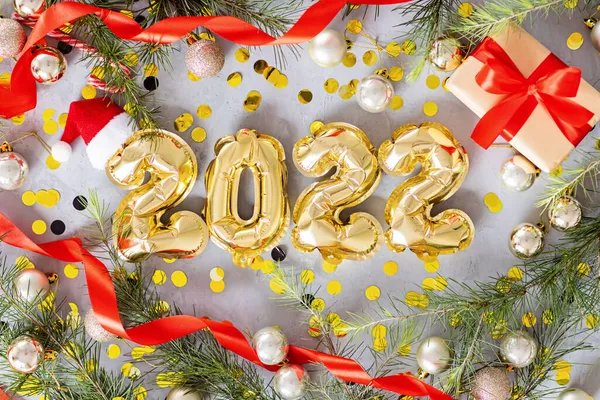 Happy new year 2022 background. Metallic balloons golden color on gray concrete background Flat lay, top view, mockup, overhead. Winter holiday celebration