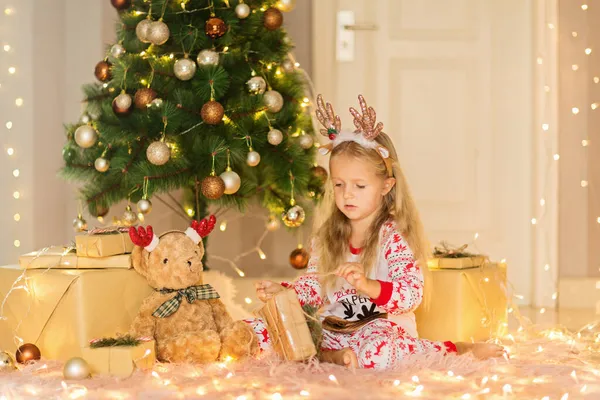 Belle petite fille caucasienne de cinq ans portant un pyjama de Noël lorsqu'elle s'amuse à la maison pendant les vacances d'hiver. Joyeux Noël et bonne année 2022 — Photo