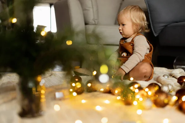 Portrait de style de vie de bébé caucasien mignon d'un an jouant avec des boules sur le sol à la maison. Joyeux Noël et bonne année 2022 — Photo