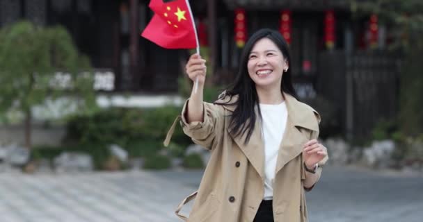 Feliz joven asiática mujer cogida de la mano china bandera nacional al aire libre. Persona que celebra el Día Nacional el 1 de octubre o el año nuevo chino 2022. Movimiento lento — Vídeos de Stock