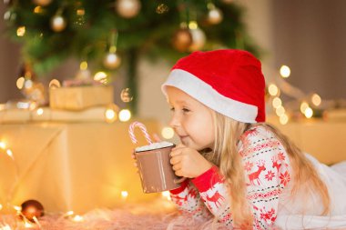 Beş yaşında güzel beyaz bir kız, kış tatilinde evde eğlenirken Noel pijaması giyiyor. Mutlu Noeller ve mutlu yıllar 2022.