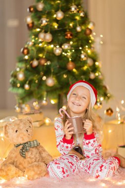 Beş yaşında güzel beyaz bir kız, kış tatilinde evde eğlenirken Noel pijaması giyiyor. Mutlu Noeller ve mutlu yıllar 2022.
