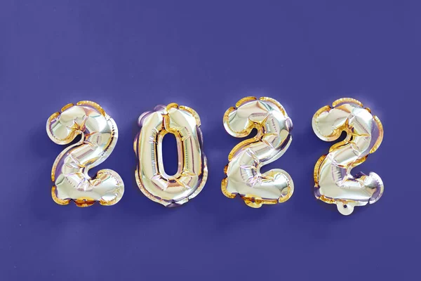 Happy new year 2022 background. Balon logam warna emas di atas kertas ungu. Warna Trendy tahun ini sangat peri. Datar berbaring, tampilan atas, mockup, overhead. Perayaan liburan musim dingin — Stok Foto
