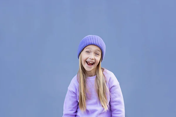 Roztomilá malá běloška osm let s blond vlasy usmívající se venku. Kluk ve stylové košili a fialové barvě pleteného klobouku. Trendy barva 2022 rok velmi peri — Stock fotografie