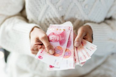 Çin Yeni Yıl kutlamaları konsepti. Genç Asyalı kadın, Bahar Festivali 'nde hediye olarak 100 Çin Yuanı' nın parasını nakit olarak tutuyor..