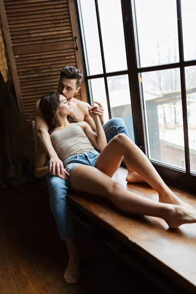 Portrait d'un charmant jeune couple à la maison. homme embrasse sa petite amie près de la fenêtre. Deux personnes se relaxent ensemble — Photo