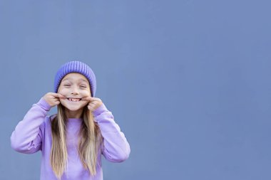 Kayıp süt dişi gösteren bir çocuk. Diş konseptini değiştir. Mor arka planda, fotokopi alanı olan, sarı saçlı, sevimli, beyaz bir kız. 2022 'nin moda rengi çok moda.