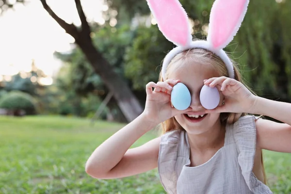 Niño feliz usando orejas de conejo cuando recoger pintado de Pascua Huevo de caza en el jardín o el parque — Foto de Stock