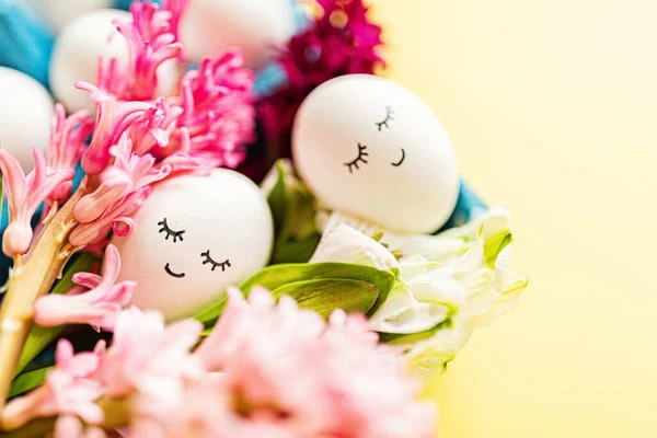 Huevos creativos de Pascua con cara bonita y ojos dormilones sobre fondo amarillo pastel. Feliz concepto de Pascua. Plano, vista superior, maqueta, plantilla, gastos generales, espacio para copiar Imagen de stock