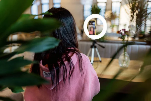 Sorridente asiatico donna streaming broadcast in moderno caffetteria e utilizzando anello lampada e telefono cellulare — Foto Stock