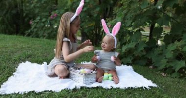 Tavşan Kulaklı İki Çocuk Bahçede ya da Parkta Paskalya Yumurtası Avı 'nı boyarken. Beyaz tatlı bir bebek ve kız kardeşi arka bahçede birlikte vakit geçiriyorlar. Yavaş çekim