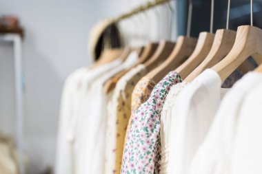 Alışveriş merkezindeki hipster moda defilesinde askıda duran farklı kadın kıyafetleri. Modayı takip eden kadınlar