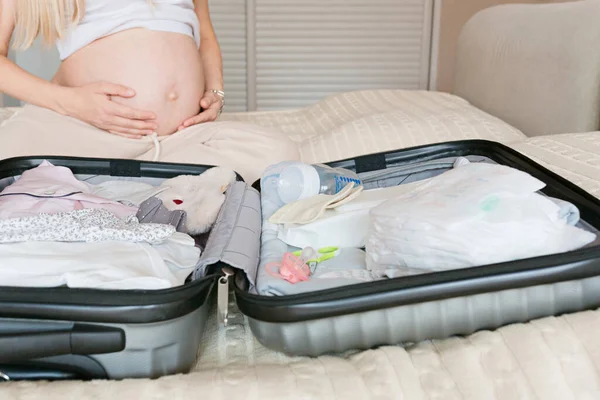 Młoda kobieta w ciąży pakująca walizkę do szpitala położniczego w domu, zbliżenie. Lista kontrolna porodu. Ciąża podczas pandemii coronavirus covid-19 — Zdjęcie stockowe