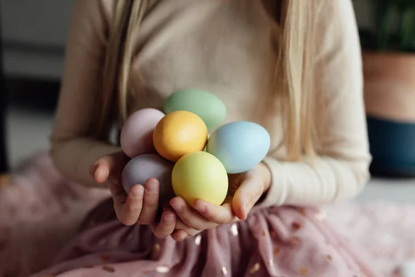 Niña caucásica feliz niño de ocho años en casa en la sala de estar con huevos de Pascua de colores. Permanecer en casa durante la pandemia del Coronavirus covid-19 — Foto de Stock