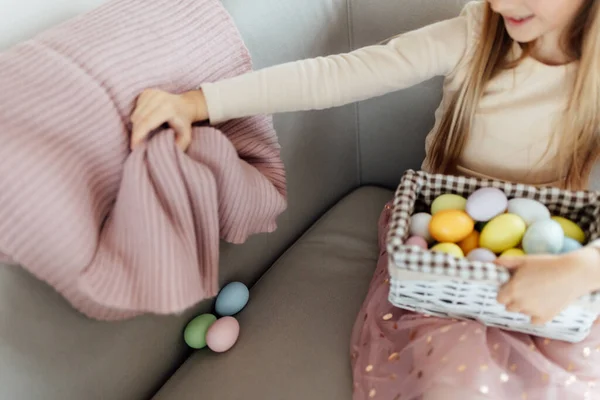 Niña caucásica feliz niño de ocho años en casa en la sala de estar con huevos de Pascua de colores. Permanecer en casa durante la pandemia del Coronavirus covid-19 — Foto de Stock