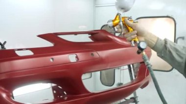 Araba servisi çalışanı kırmızı araba tamponuna son rötuşları yaptı