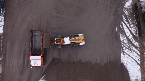 Погрузчик кладет грунт в кузов грузовика на стройплощадке — стоковое видео