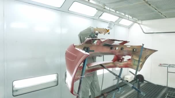 Рабочий окрашивает бампер автомобиля красным с помощью безвоздушного спрея — стоковое видео