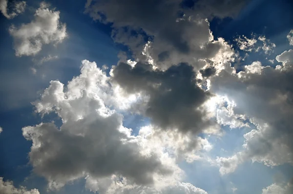 Sluneční paprsky zpoza mraků na modré obloze — Stock fotografie