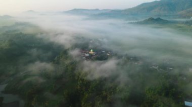 Aerial view. flying over the village and fog in the morning. Dramatic and beautiful