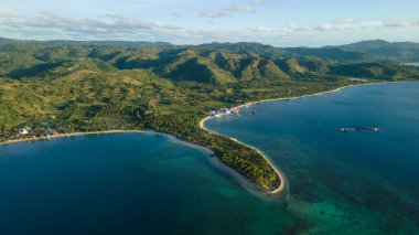 Tropikal adanın drone görüntüsü, tepeler ve ormanlar akşam kumsalda