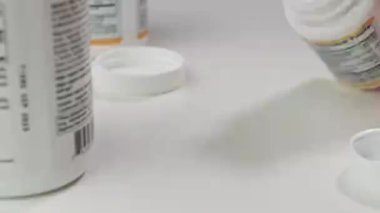 Cam bir kavanoz düşer ve sarı tabletler beyaz bir eş masasına düşer.