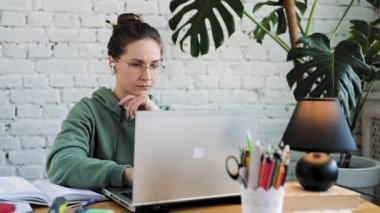 Dizüstü bilgisayarda yazı yazan ciddi bir beyaz kız öğrenci ders hazırlıyor.