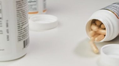 Cam bir kavanoz düşer ve sarı tabletler beyaz bir eş masasına düşer.