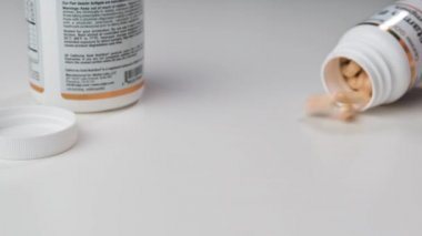 Cam bir kavanoz düşer ve sarı tabletler beyaz bir eş masasına düşer.