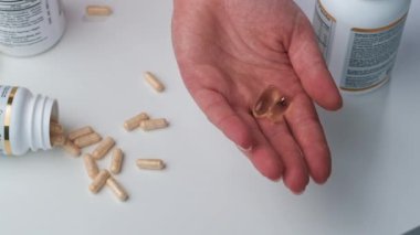 İlaçlar. Ağır çekim. Kadın avuç içini haplarla kaplıyor, beyaz arka planda balık yağı omega-3. Yakın plan.. 