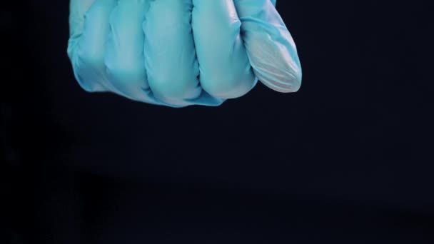 Mão das mulheres em uma luva médica apertada no punho desaperta pílulas de palma, cápsulas em gel shell no fundo preto. Ómega-3, multivitaminas, cálcio, antibióticos. Saúde, vitaminas complexas. Serviços de saúde — Vídeo de Stock