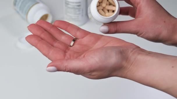 Sport, gezonde levensstijl, geneeskunde, voedingssupplementen en mensen concept - close-up van de vrouw gieten pillen van pot tot hand — Stockvideo