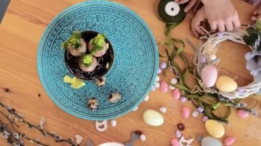 Kızı olan genç anne paskalya bayramı masasını tavşan ve yumurta süsleme çelengi ile hazırlıyor. Yakın plan. Yukarıdan görüntüle