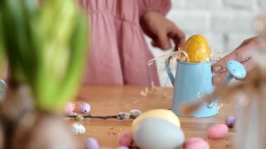 Mutlu güzel kız çocuğu, bahar zamanı evde Paskalya için sarı yumurta boyarken eğleniyor. Çocuk yumurta boyuyor. Mutlu aile Paskalya için hazırlanırken ev dekorasyonunun keyfini çıkarıyor..