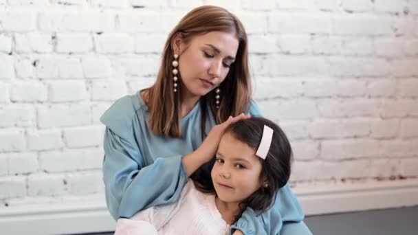 Aimer tendre jeune maman tenant adorable fille mignonne fille embrassant petit enfant. Bonne mère affectueuse câlinant avec bébé debout à la maison. 4k — Video