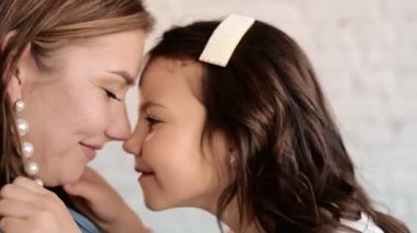 Sevgi dolu, genç bir anne, sevimli bir kız çocuğu kucaklıyor, küçük bir çocuğu öpüyor. Mutlu şefkatli anne evde duran bebeğe sarılıyor..