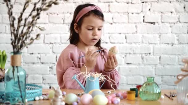 Menina bonita feliz que se diverte durante a pintura de ovos para a Páscoa na primavera em casa. Criança a pintar ovos. Família feliz se preparando para a Páscoa enquanto desfruta de decoração DIY em casa. 4K — Vídeo de Stock