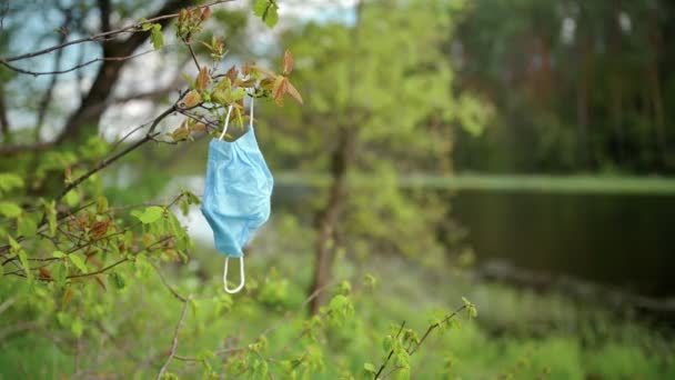 Gebrauchte Mundschutz liegt auf dem Boden in einem Stadtpark, im Hintergrund laufen Menschen — Stockvideo