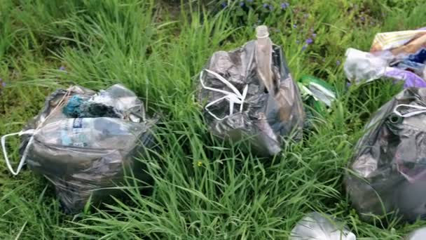 Un pacchetto di rifiuti di plastica si trova nella foresta su una strada forestale, inquinamento della natura, spazzatura e natura, il sole, primo piano, rallentamento — Video Stock